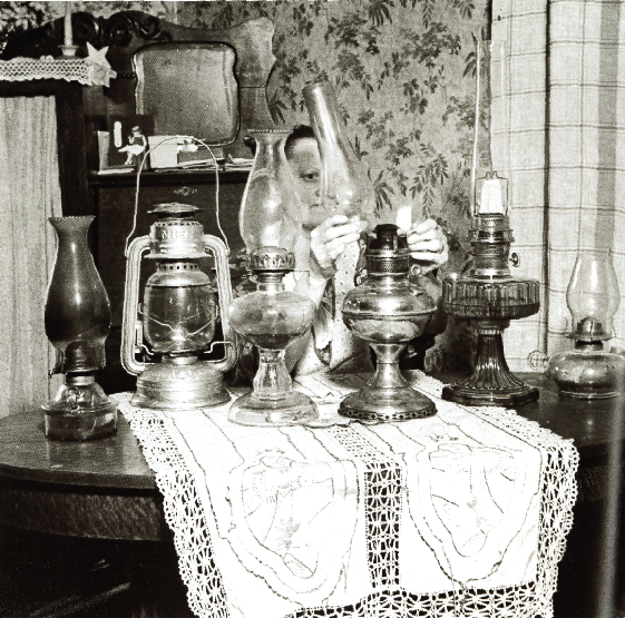 A rural woman carefully reassembles a kerosene lamp after cleaning it. Photo Source: "The Next Greatest Thing," published by NRECA