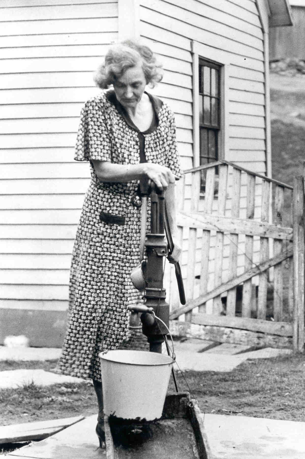 Woman at the water pump. Photo Source: "The Next Greatest Thing" published by NRECA
