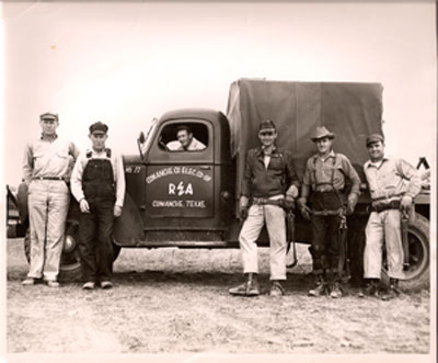 Texas line crews who worked with their newly formed local co-op pose with a truck branded with the REA logo.