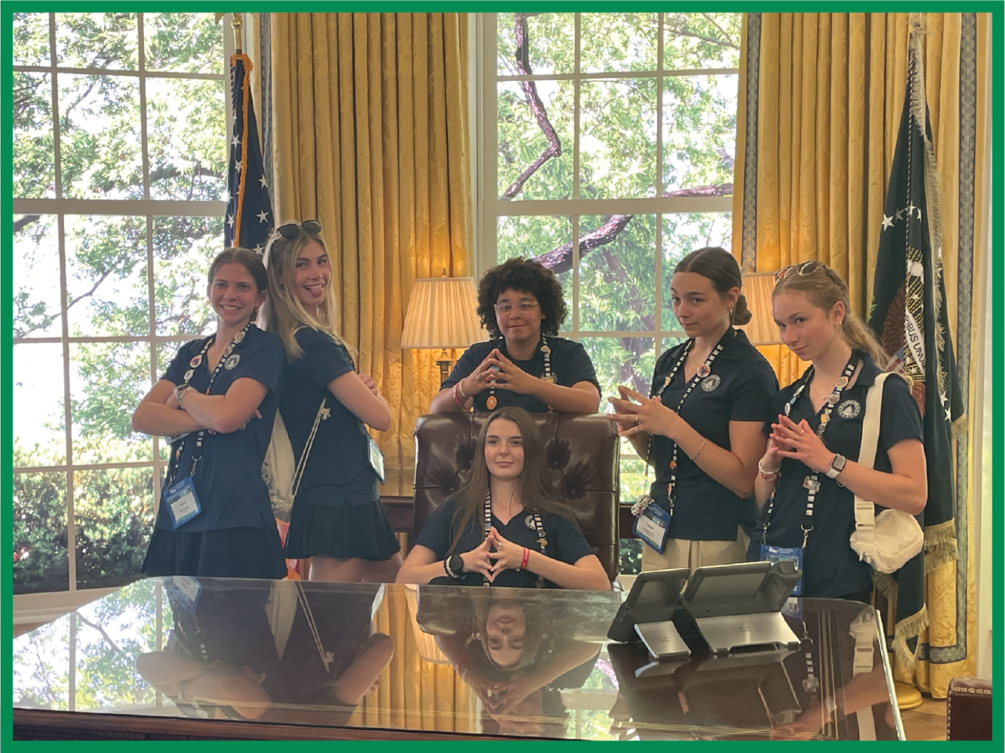 A group of 2025 Youth Tour students pose behind a replica of the President's desk in the People's House Museum