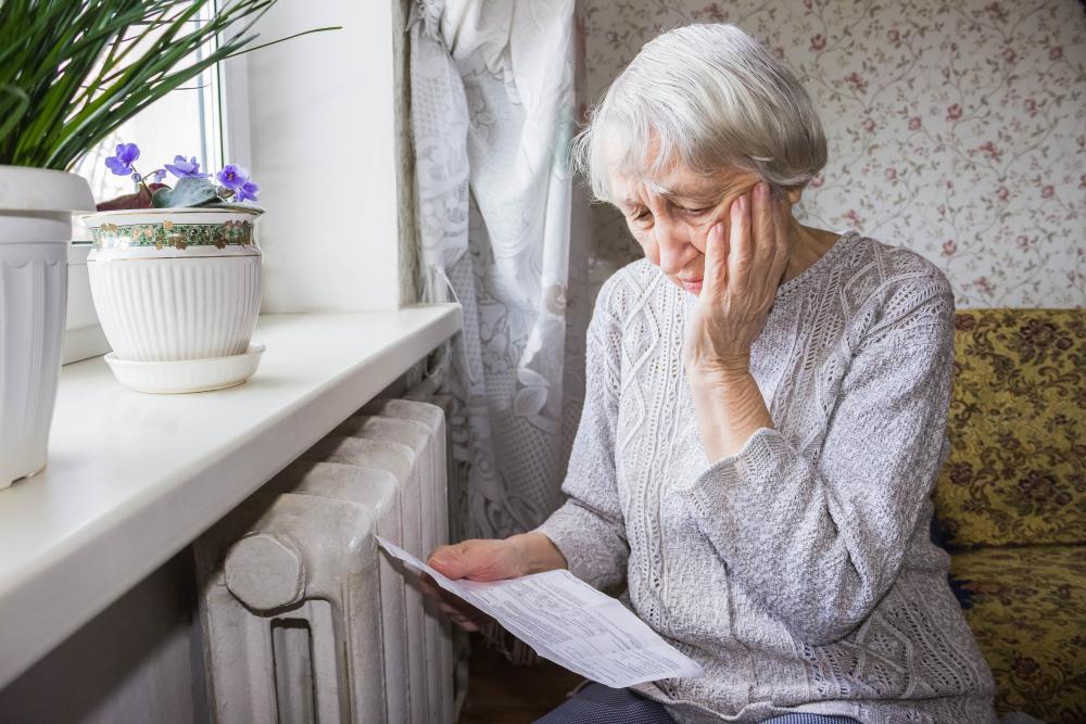 A woman sitting by her heater, looking down at her electric bill