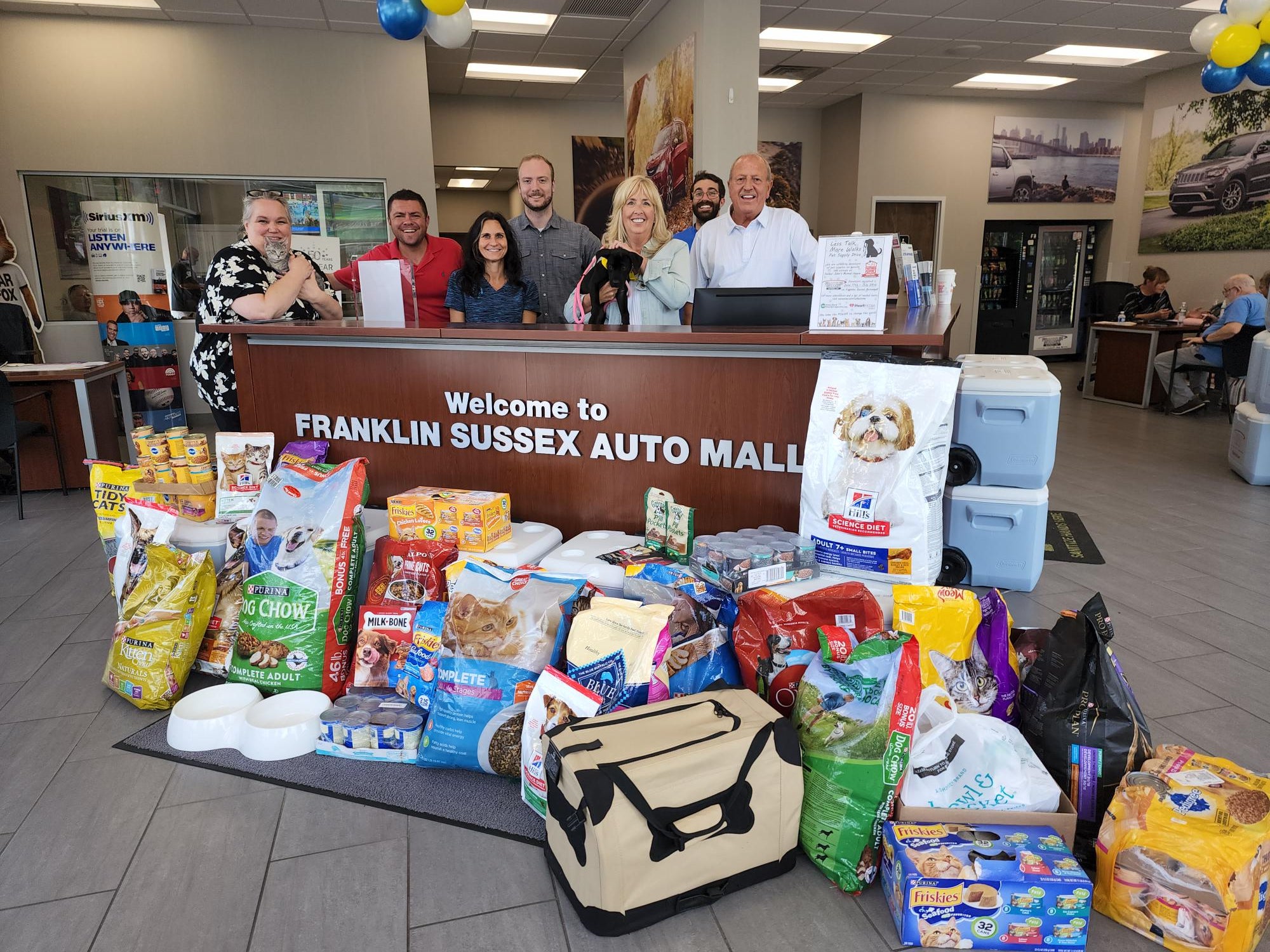 Pictured: representatives from Sussex Rural Electric Cooperative, Franklin Sussex Auto Mall, 102.3 WSUS, Wantage Veterinary Clinic, and Father John's Animal House with just a portion of the donations to the Less Talk, More Walks Pet Supply Drive, which totaled 775 lbs of pet food and supplies!