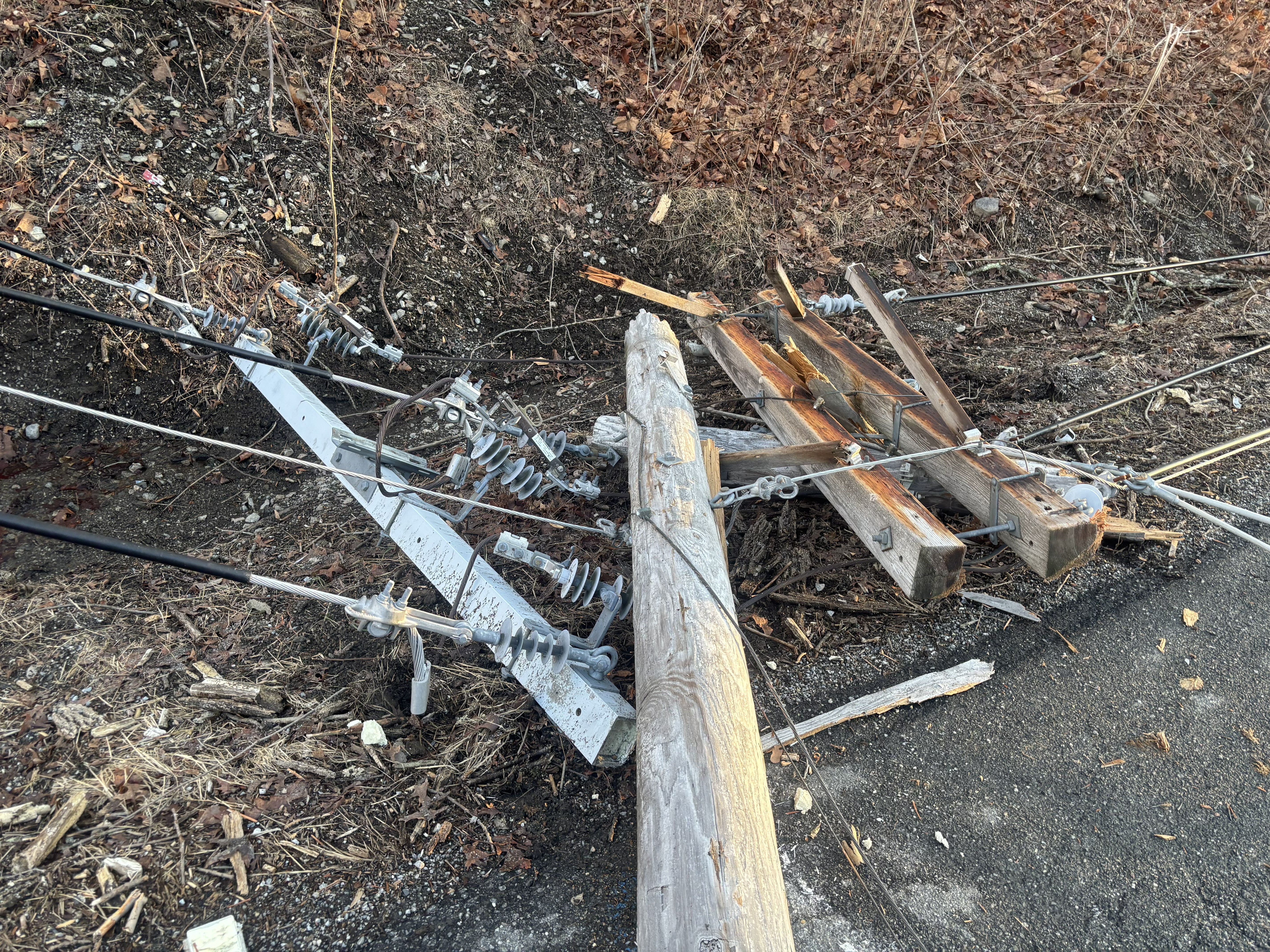 Photo showing the top of a utility pole, laying broken on the ground