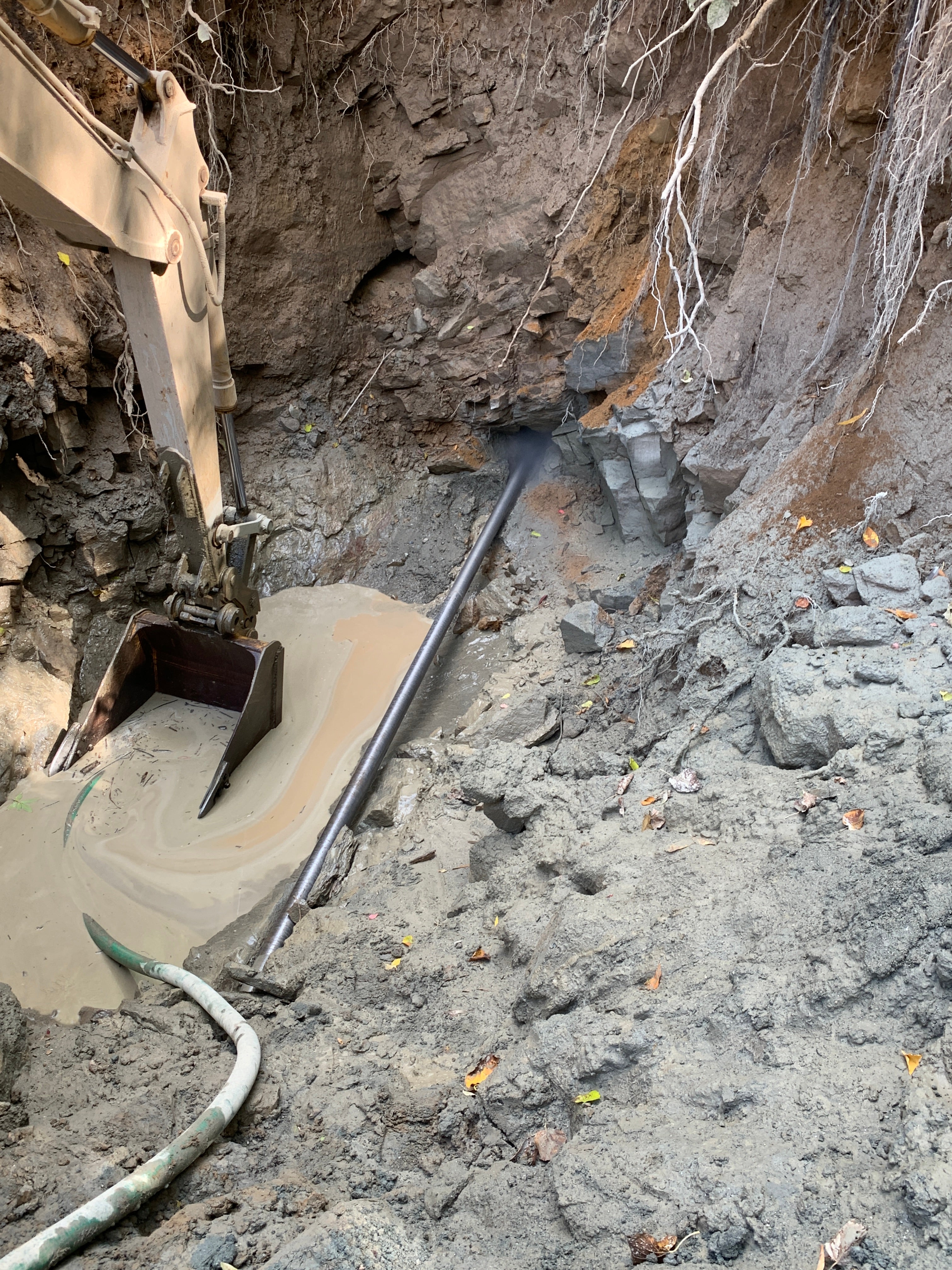 Image of the directional boring drill penetrating rock, next to an excavator